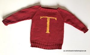 Pullover in rot mit einem aufgestickten gelben T im Maschenstich